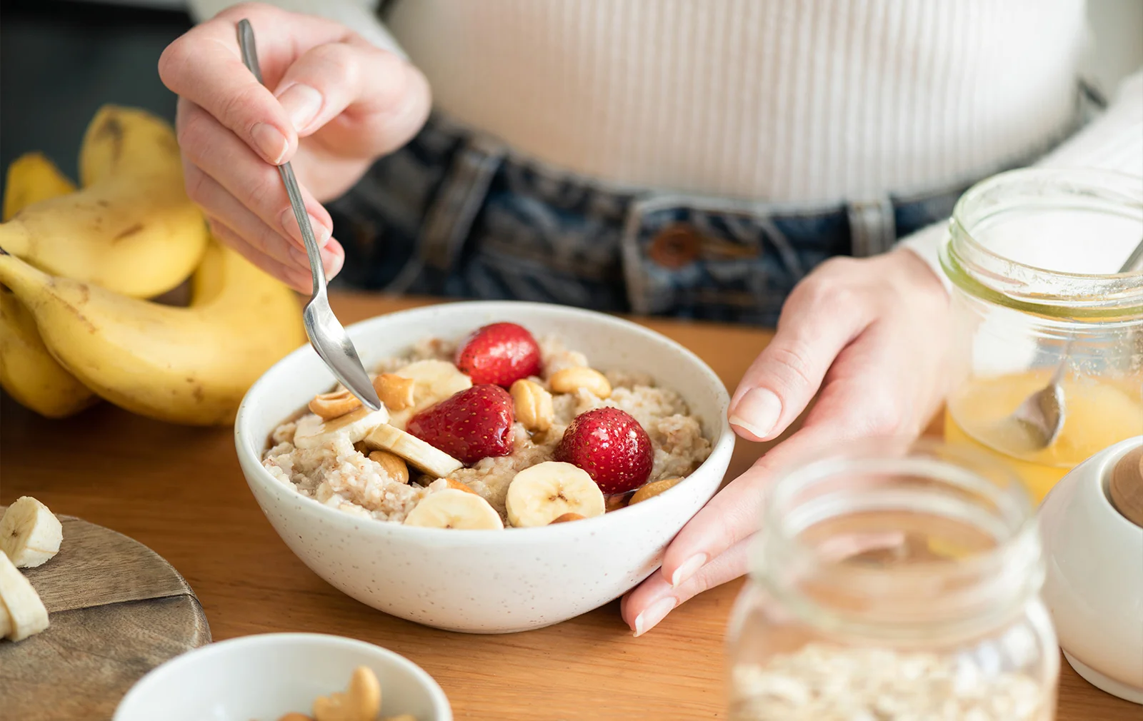 Tazón de bebida vegetal de avena con fresas, plátano y frutos secos, acompañado de ingredientes naturales.