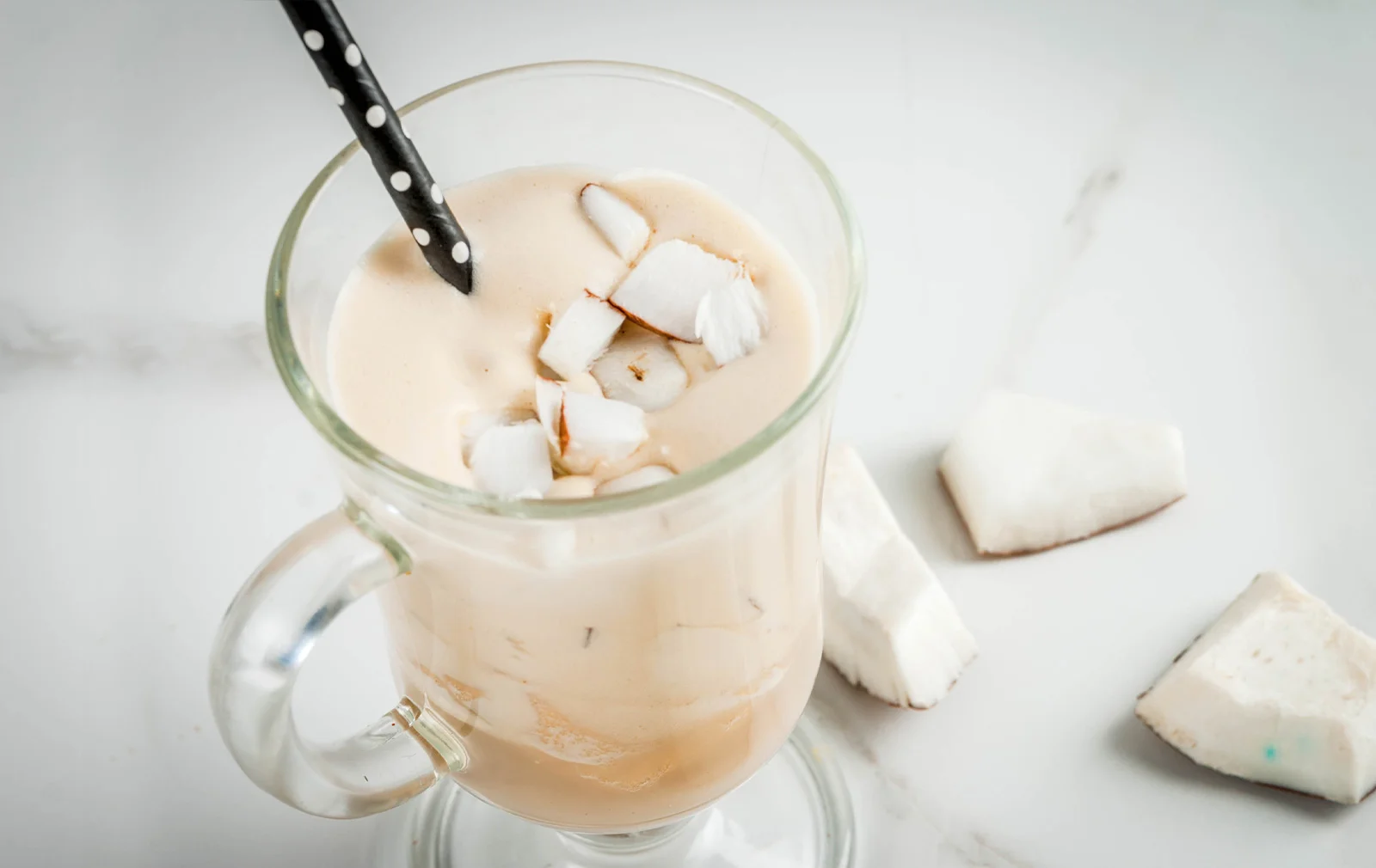 Un bicchiere colmo di rinfrescante frappè con al latte di cocco OsaSì senza zuccheri, accompagnato da una cannuccia.