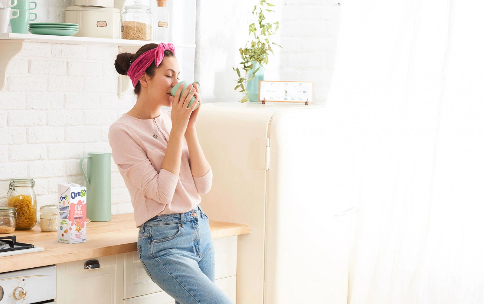 Una niña intolerante a la lactosa tomando una taza de bebida vegetal de avena de avena OraSì feliz y relajada, porque es una excelente alternativa a la leche de origen animal.