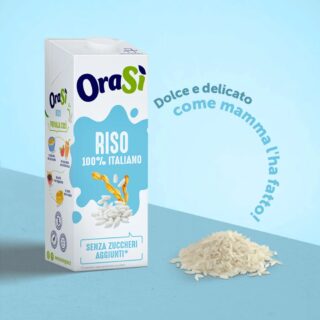 Envase de bebida vegetal de arroz OraSì 100% italiana, sin azúcares añadidos, junto a un puñado de granos de arroz, con el mensaje "Dulce y delicado como mamma l'ha fatto".