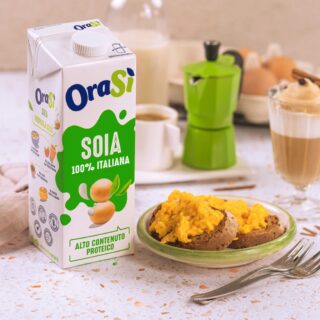 Un desayuno con bebida vegetal de soya OraSì 100% italiana, acompañado de tostadas con revuelto de huevo, una cafetera y un vaso de café.